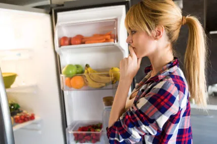 Standing in front of the refrigerator, unsure what to eat.